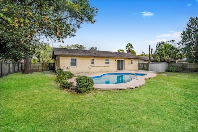 rear view of house with stucco siding, a lawn, a patio, a fenced backyard, and a storage shed