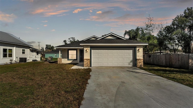 view of front of home with driveway, a garage, fence, cooling unit, and a yard