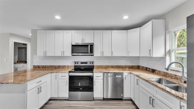 kitchen with appliances with stainless steel finishes, a sink, and white cabinets