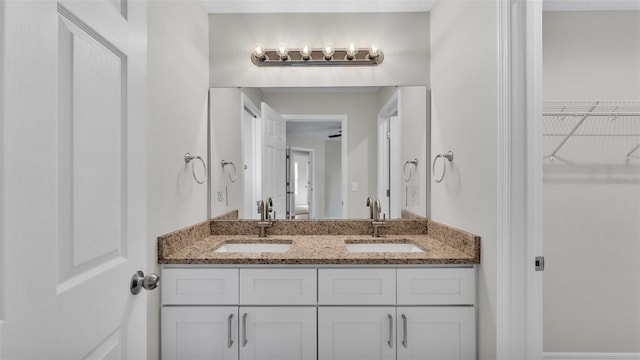 bathroom featuring double vanity, a sink, and a walk in closet