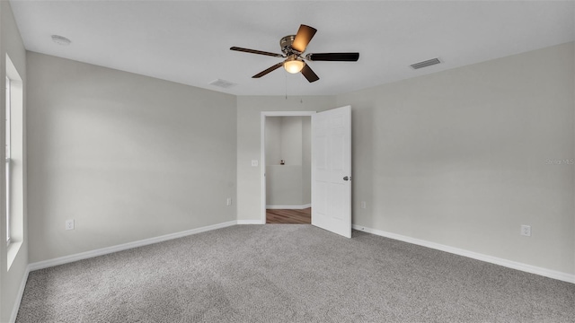 carpeted spare room featuring ceiling fan, visible vents, and baseboards