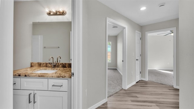 bathroom with ceiling fan, wood finished floors, vanity, and baseboards