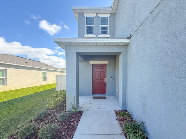 entrance to property featuring a yard and stucco siding