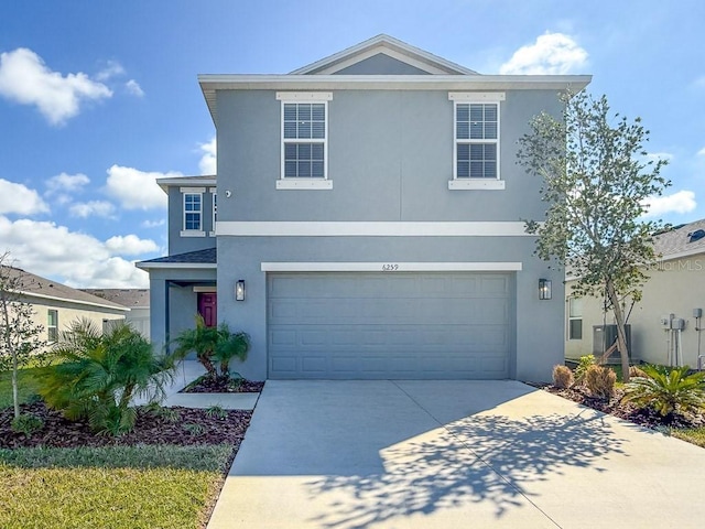 traditional-style house featuring driveway, an attached garage, and stucco siding