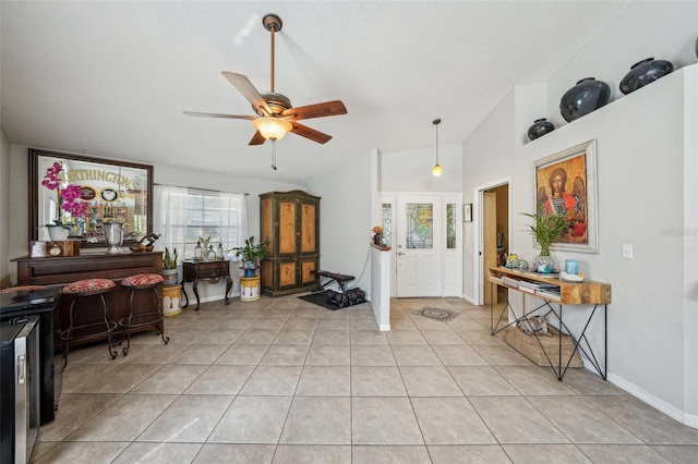 foyer entrance with light tile patterned floors, ceiling fan, a textured ceiling, lofted ceiling, and baseboards