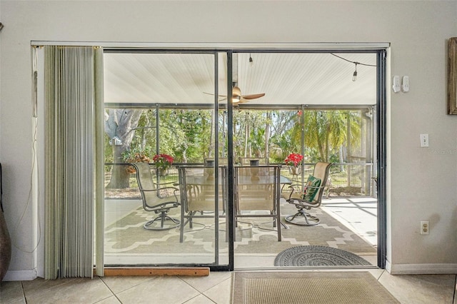 doorway to outside featuring a sunroom, tile patterned flooring, baseboards, and a ceiling fan