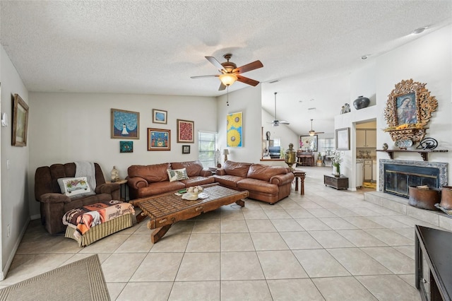 living room with light tile patterned floors, ceiling fan, a textured ceiling, lofted ceiling, and a fireplace