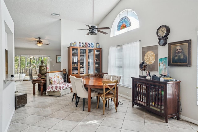 tiled dining area featuring baseboards, visible vents, a ceiling fan, a towering ceiling, and a textured ceiling