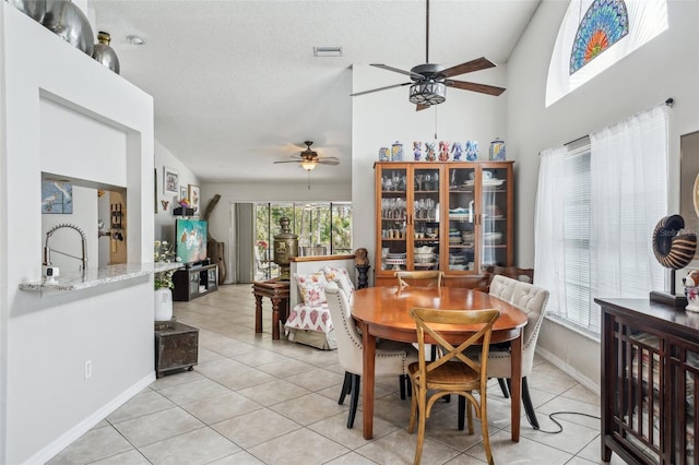 dining area with a textured ceiling, light tile patterned floors, visible vents, baseboards, and a ceiling fan