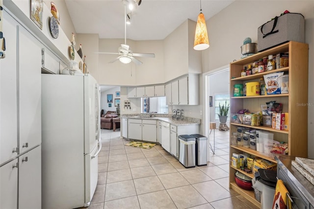 kitchen with light tile patterned floors, freestanding refrigerator, a high ceiling, light countertops, and open shelves