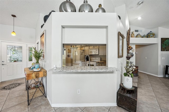 kitchen featuring white appliances, vaulted ceiling, a textured ceiling, and tile patterned floors