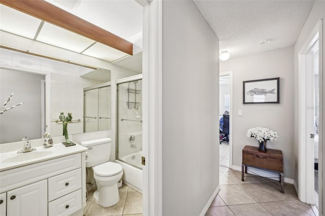 ensuite bathroom with ensuite bathroom, a textured ceiling, toilet, vanity, and tile patterned floors