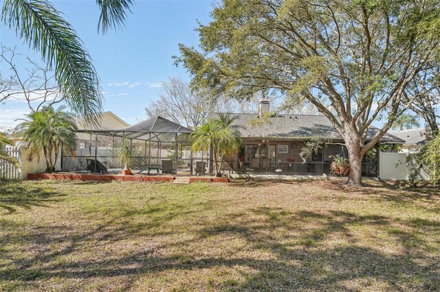 rear view of house with a patio area, glass enclosure, fence, and a lawn