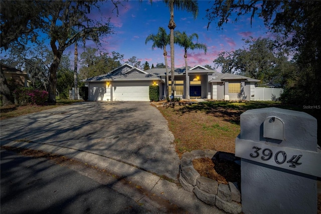 ranch-style home with a garage, driveway, and fence