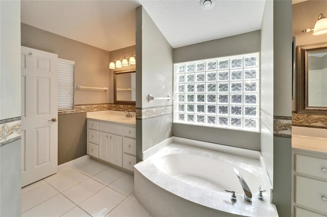 full bathroom with tile patterned floors, a sink, a garden tub, a textured ceiling, and two vanities