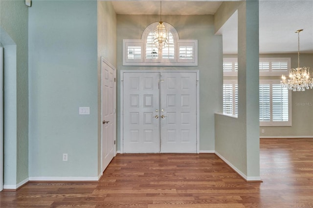 foyer with baseboards, wood finished floors, and a notable chandelier