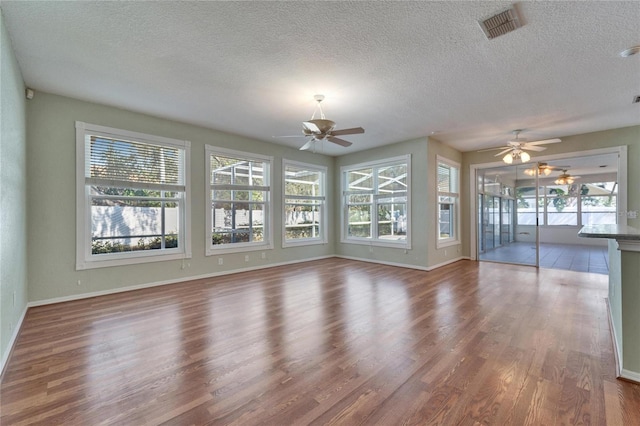 interior space with a textured ceiling, visible vents, and wood finished floors