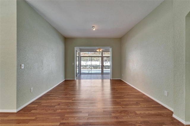 spare room with baseboards, wood finished floors, and a textured wall