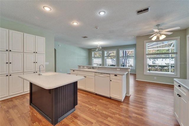 kitchen featuring a kitchen island with sink, dishwasher, visible vents, and a sink