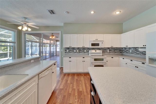 kitchen with white appliances, visible vents, light countertops, and backsplash