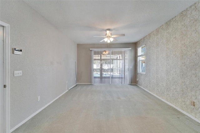 carpeted spare room with a textured ceiling, ceiling fan, and baseboards