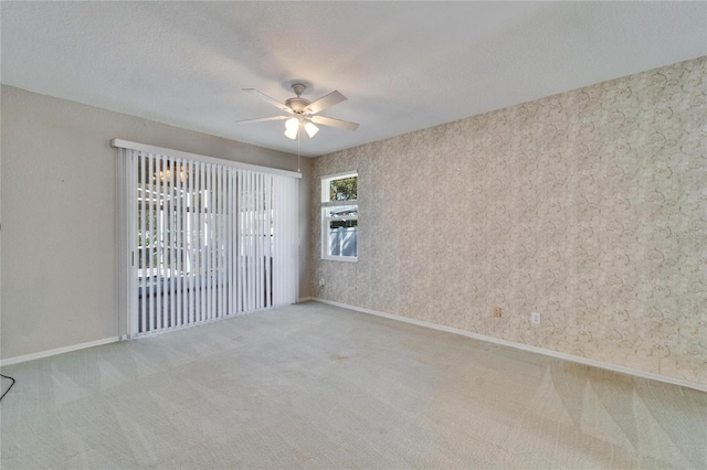 carpeted spare room with a textured ceiling, a ceiling fan, and baseboards