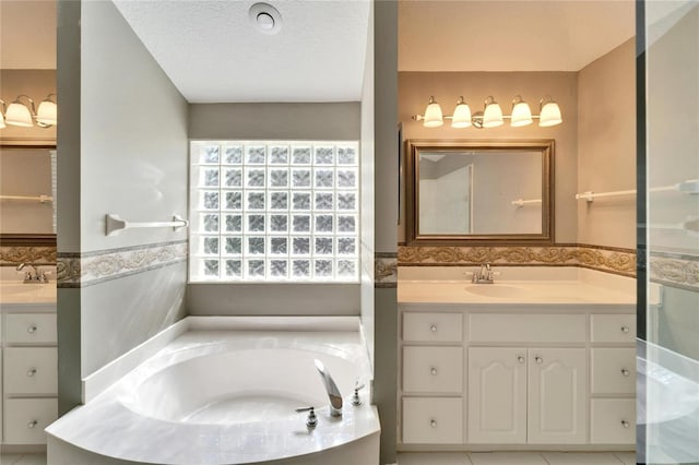 full bathroom with a textured ceiling, two vanities, a sink, and a bath