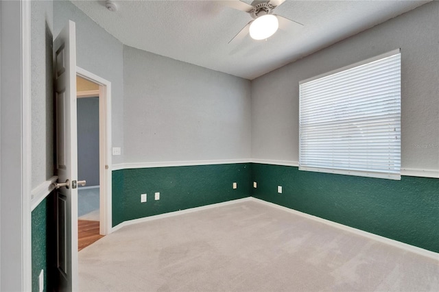 carpeted empty room with ceiling fan, a textured ceiling, and a textured wall