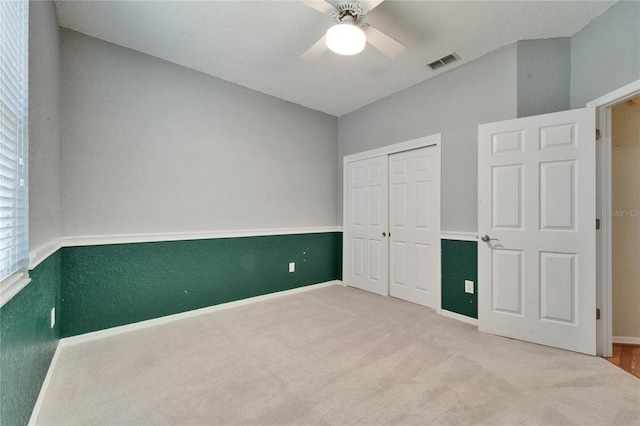 unfurnished bedroom with a ceiling fan, carpet, visible vents, and a closet