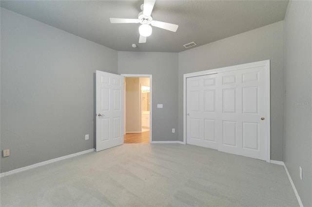 unfurnished bedroom with light carpet, a closet, visible vents, and baseboards