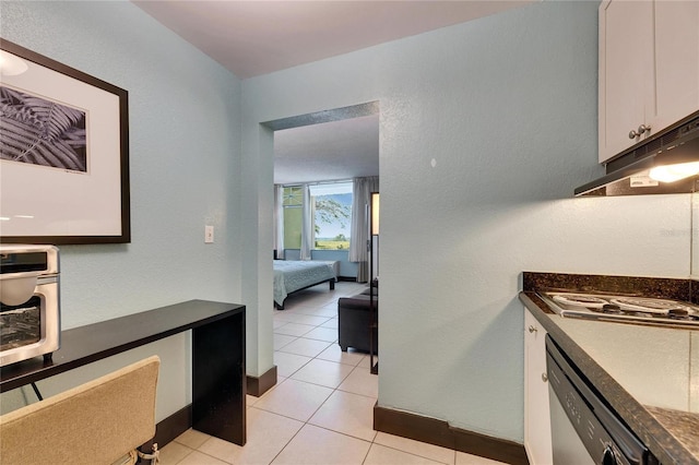 kitchen with dark countertops, electric stovetop, dishwasher, and under cabinet range hood