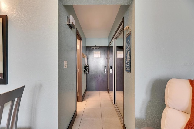 corridor featuring light tile patterned floors and a textured wall