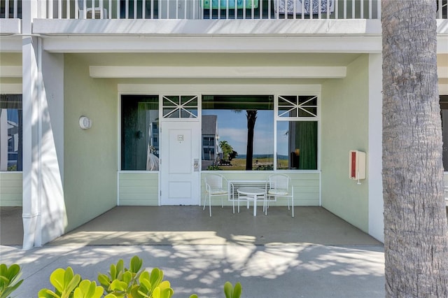 property entrance featuring a balcony and stucco siding