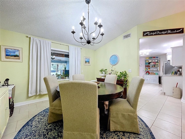 dining room with a notable chandelier, light tile patterned floors, visible vents, vaulted ceiling, and a textured ceiling