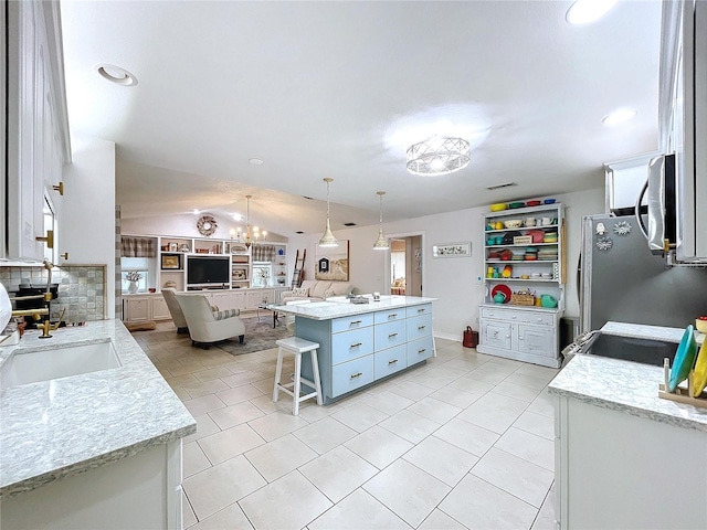 kitchen with a breakfast bar, light tile patterned floors, stainless steel appliances, open floor plan, and vaulted ceiling