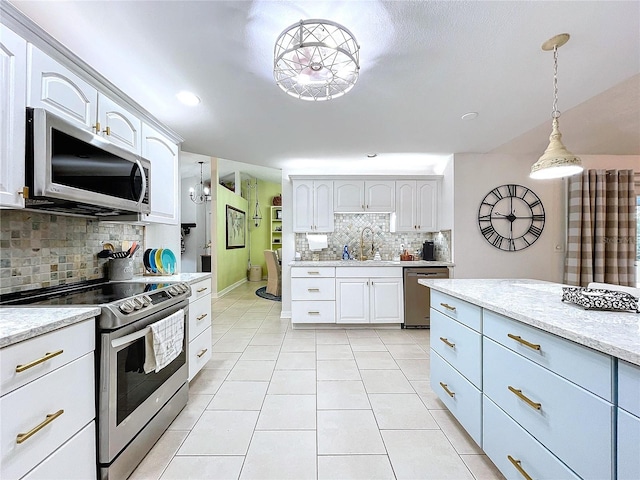 kitchen with pendant lighting, appliances with stainless steel finishes, light tile patterned flooring, a sink, and light stone countertops