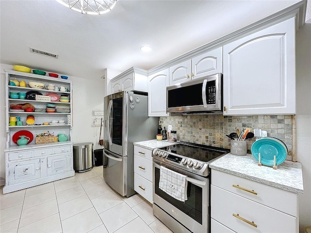 kitchen with light tile patterned floors, stainless steel appliances, visible vents, white cabinets, and backsplash