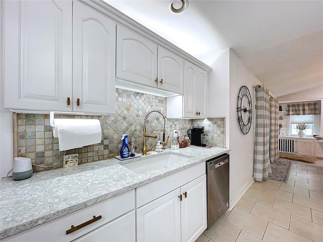 kitchen with light tile patterned floors, white cabinets, a sink, light stone countertops, and dishwasher