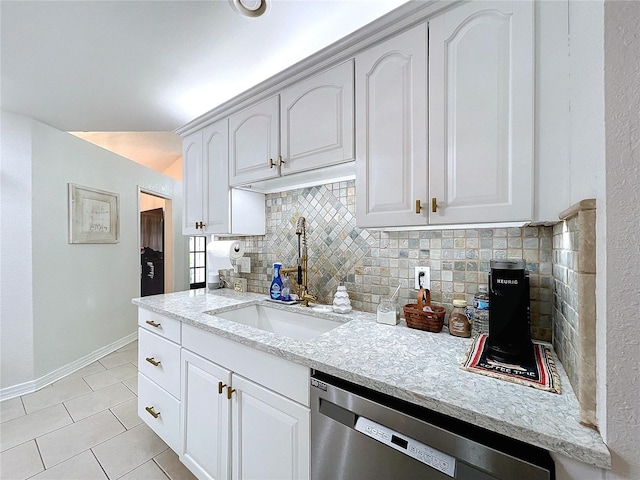 kitchen featuring light tile patterned floors, backsplash, stainless steel dishwasher, a sink, and baseboards