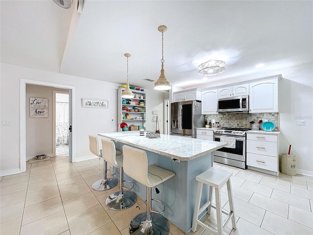 kitchen with light tile patterned floors, stainless steel appliances, backsplash, a kitchen island, and a kitchen breakfast bar