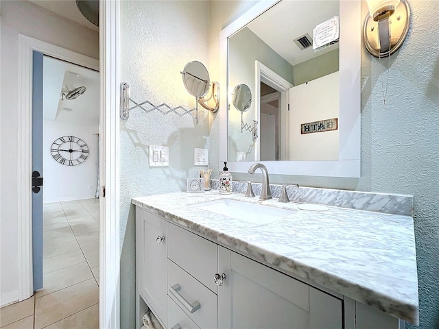 bathroom with a textured wall, visible vents, and tile patterned floors