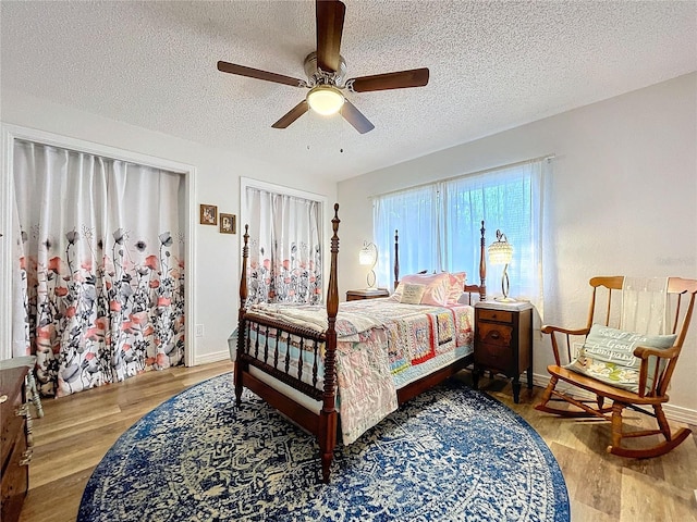 bedroom featuring baseboards, a textured ceiling, a ceiling fan, and wood finished floors