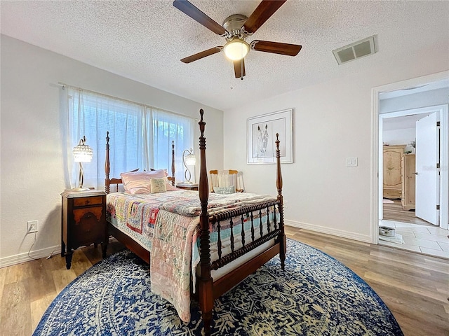 bedroom with visible vents, a textured ceiling, and wood finished floors