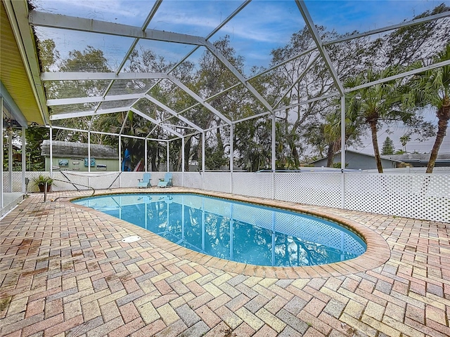 view of swimming pool featuring a fenced in pool, glass enclosure, and a patio area