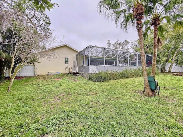 view of yard with glass enclosure and fence