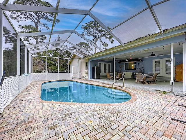 outdoor pool featuring glass enclosure, french doors, and a patio area