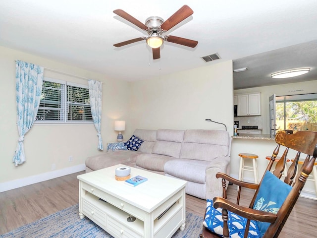 living area with visible vents, ceiling fan, baseboards, and wood finished floors