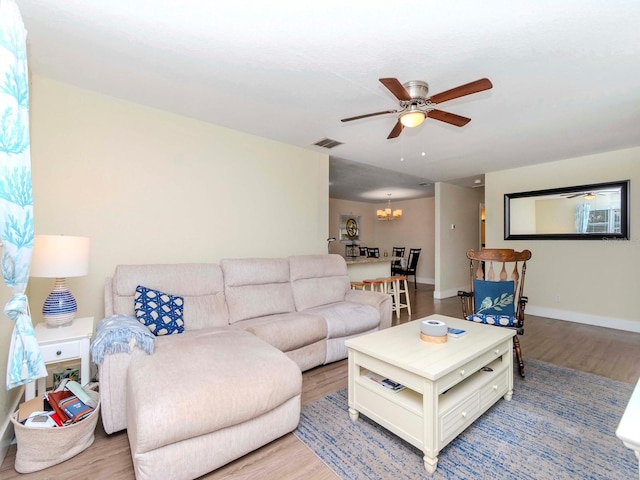 living area featuring baseboards, visible vents, wood finished floors, and ceiling fan with notable chandelier