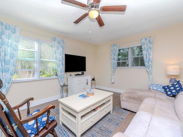 living room with ceiling fan, baseboards, and wood finished floors