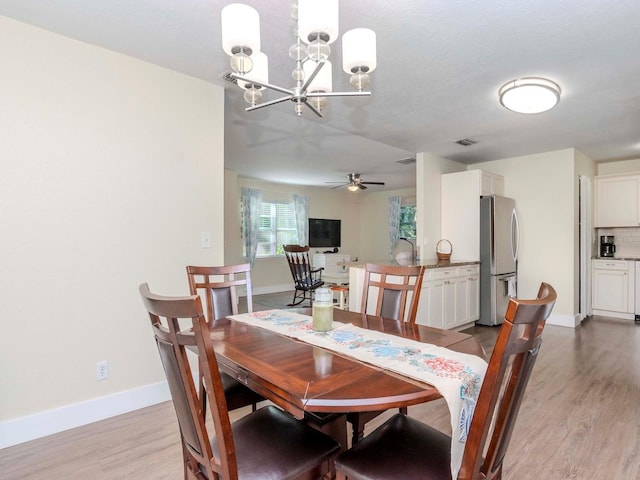 dining area with visible vents, light wood-style flooring, baseboards, and ceiling fan with notable chandelier